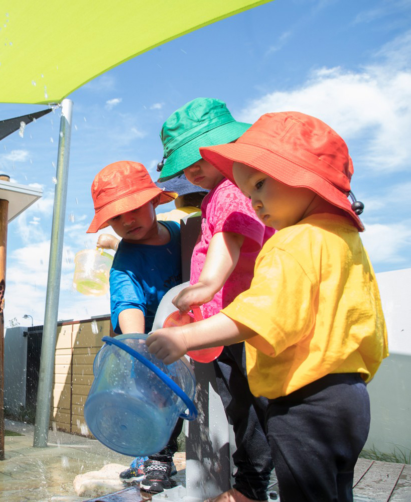 Children learning by playing with water, sharing their fun - Siblings Early Learning qld